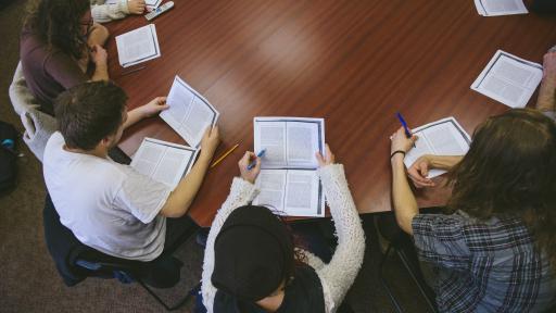 Group of students reading essay on round table