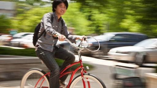 student riding red bike outside